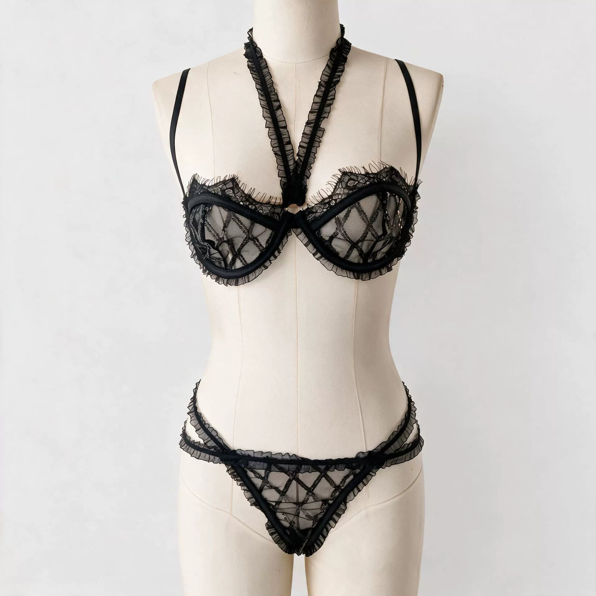 New French-style sexy lingerie set featuring a geometric grid-patterned mesh bra with sequin detailing and lettuce-edge trim, designed to minimize the appearance of a larger bust.
